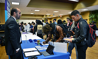 Student at an on-campus career fair, talking to a recruiter.