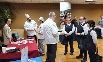HCAT students at an on-campus career fair, talking to a recruiter.