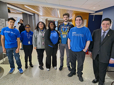 7 students standing together, most wearing SUNY Schenectady shirts. 
