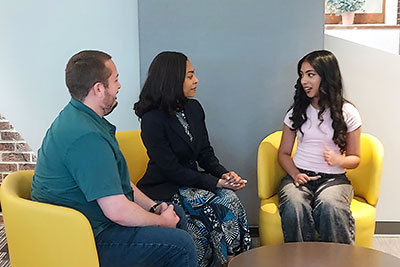 Dr. Reaves sitting with two students, intently listening while one student is talking.