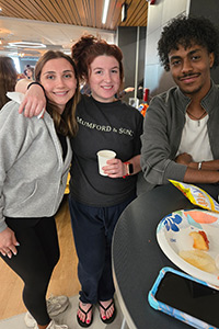 Three students standing together smiling for the camera.