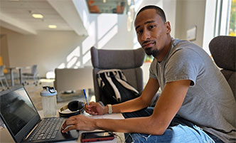 Rayshawn Floyd working on a laptop in the Begley Learning Commons.
