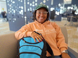 Adult student sitting in the Learning Commons with her backpack.