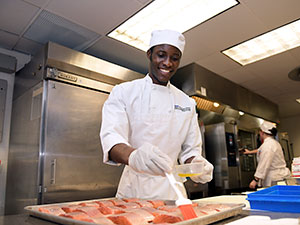 Student in uniform, working in the Casola Dining Room