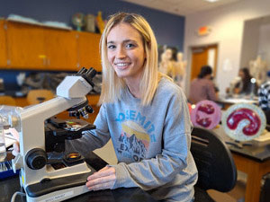 Student sitting at a microscope in the bio lab.