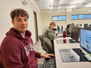 Two students sitting at computers in a class.