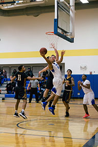 Men's basketball player making a shot from under the hoop.