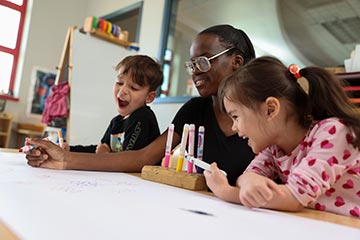 Early Childhood student working with two young children in the Integrated Preschool Laboratory.