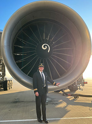 Joshua Ross standing by a United Airlines airplane engine.