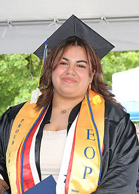 Female EOP student in cap, gown and EOP stoll, stands on stage at commencement.