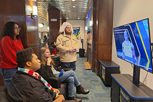 Group of students gathered around a TV in the eSports Arena's casual gaming area.