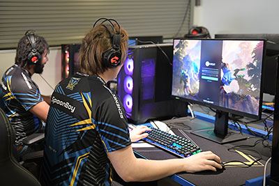 Two students in the eSports arena, playing on the computers.  