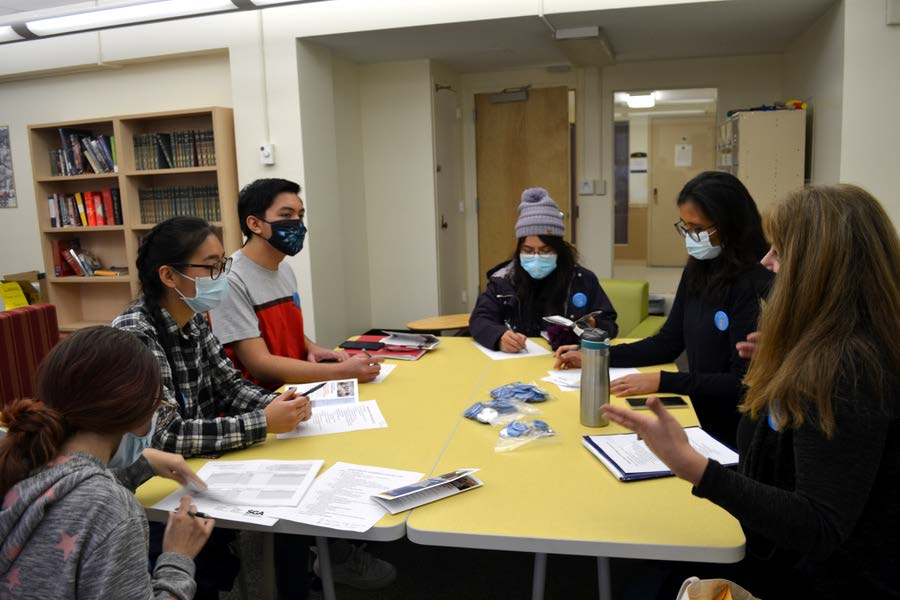 English language learning students working around a table together.