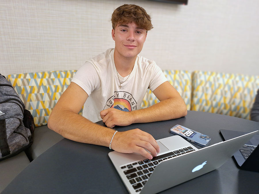 White male student working on a laptop in the Begley Learning Commons.