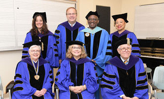 President Moono standing with members of the Board of Trustees at Commencement .
