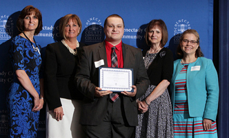 Student, standing with donors, receiving an award at Honors Convocation