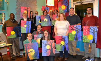 Alumni and friends displaying their work from an alumni mixer at a paint and sip night.