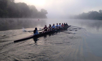 Rowers in a crew scull on the Mohawk River at dawn.
