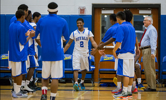 Men's basketball team members giving high-fives before the start of a game.