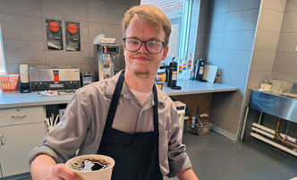 Student worker in the cafe, holding a cup of coffee.