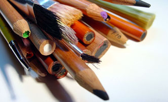 Colored pencils, paint brushes, charcoal pencils all bundled together.