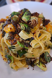 Butternut Squash and Brussels Sprout Aglio e Olio, served during the Autumn Harvest week at Casola Dining Room, a cheese souffle served with butter bib lettuce salad.