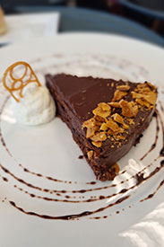 Chocolate cake on a plate with decorative icing on plate.