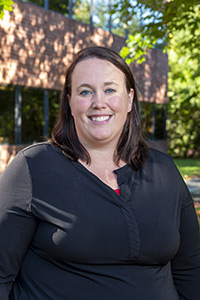 Dr. Melissa Evans wearing a black shirt, stands outside, smiling for the camera.