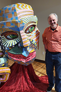Artist standing with their large sculpture in the Rise Gallery.