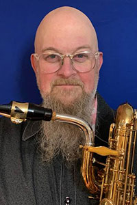 Headshot of Bradd Hubbard holding his baritone saxophone.