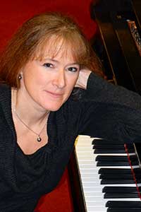 Headshot of Maura Hall, leaning on a piano.