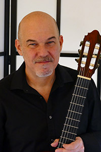 Headshot of Paul Quigley, holding a guitar. 