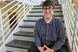 Zechariah Alles sitting on the stairs inside the School of Music. 