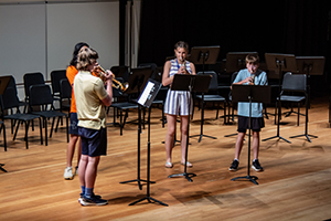 Four trumpet students on stage in the auditorium.