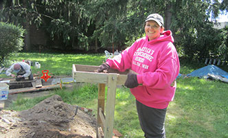 Woman standing at a sifter at an archaeology dig site.