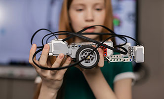 Young girl holding a Lego robotics project.