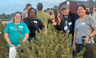 SUNY Schenectady cannabist students in front of a hemp plant.