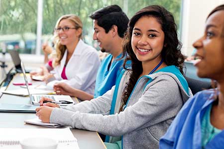 Healthcare workers, in scrubs, in a classroom setting. 