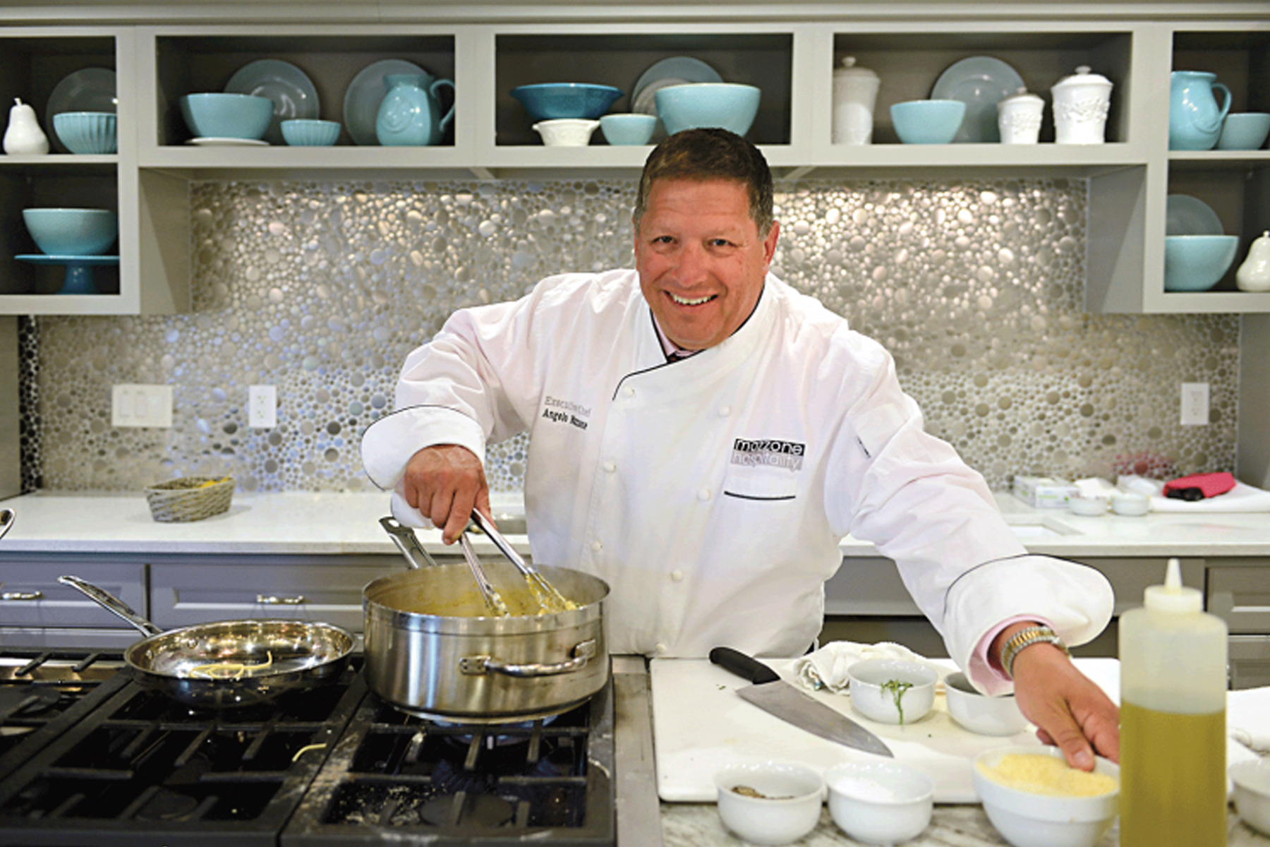 Angelo Mazzone, wearing chef's uniform, cooking in kitchen