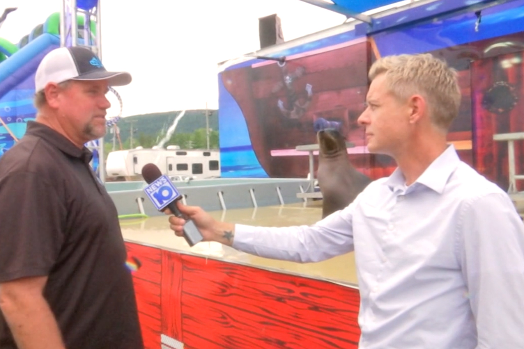 James De La Fuente, holding NEWS10 microphone,  doing interview at Altamon Fair, sea lion in the background