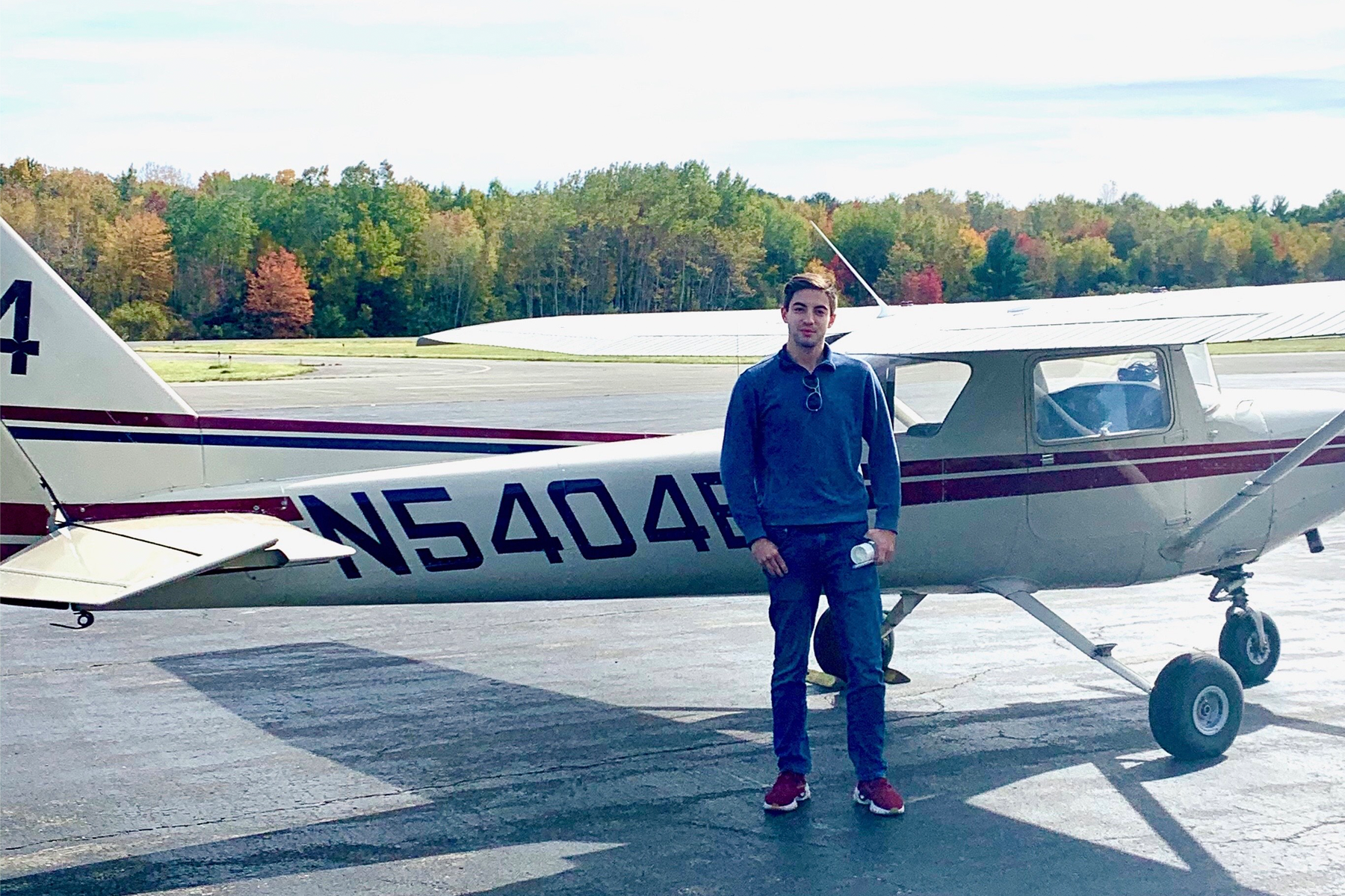Lorenzo Cruz '25 stands in front of a small airplane.