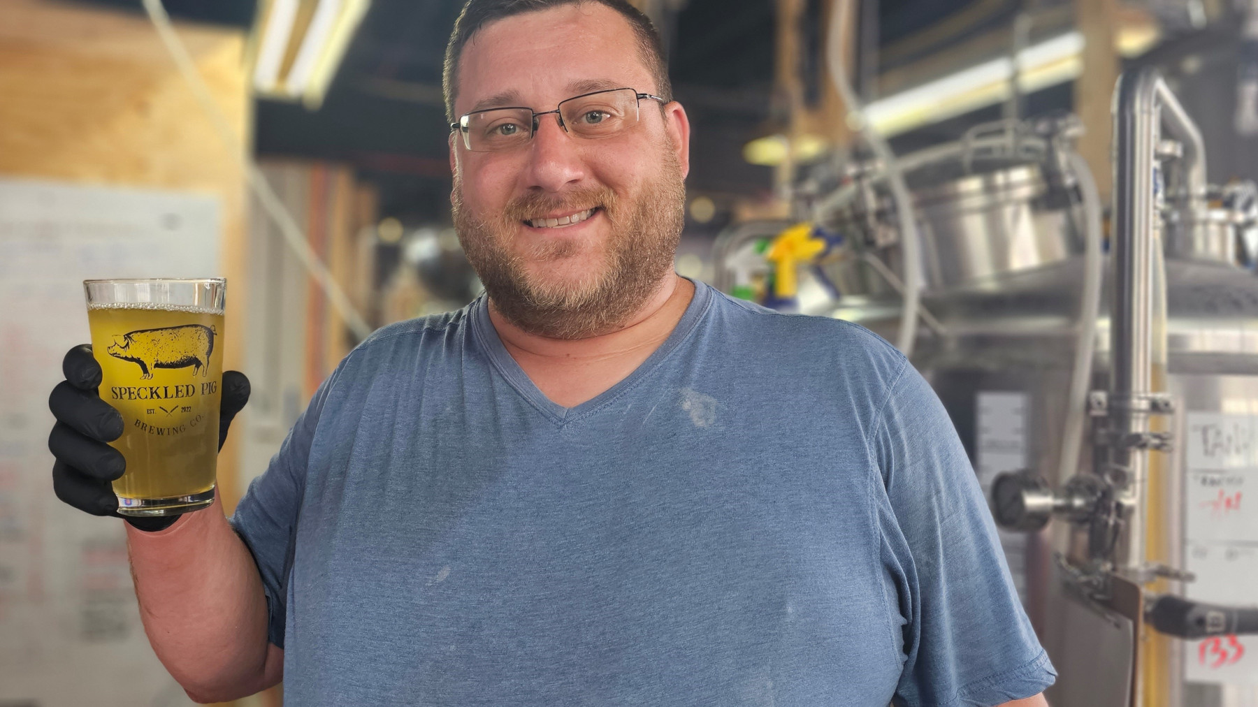 Pete Woznack holding Speckled Pig glass of beer