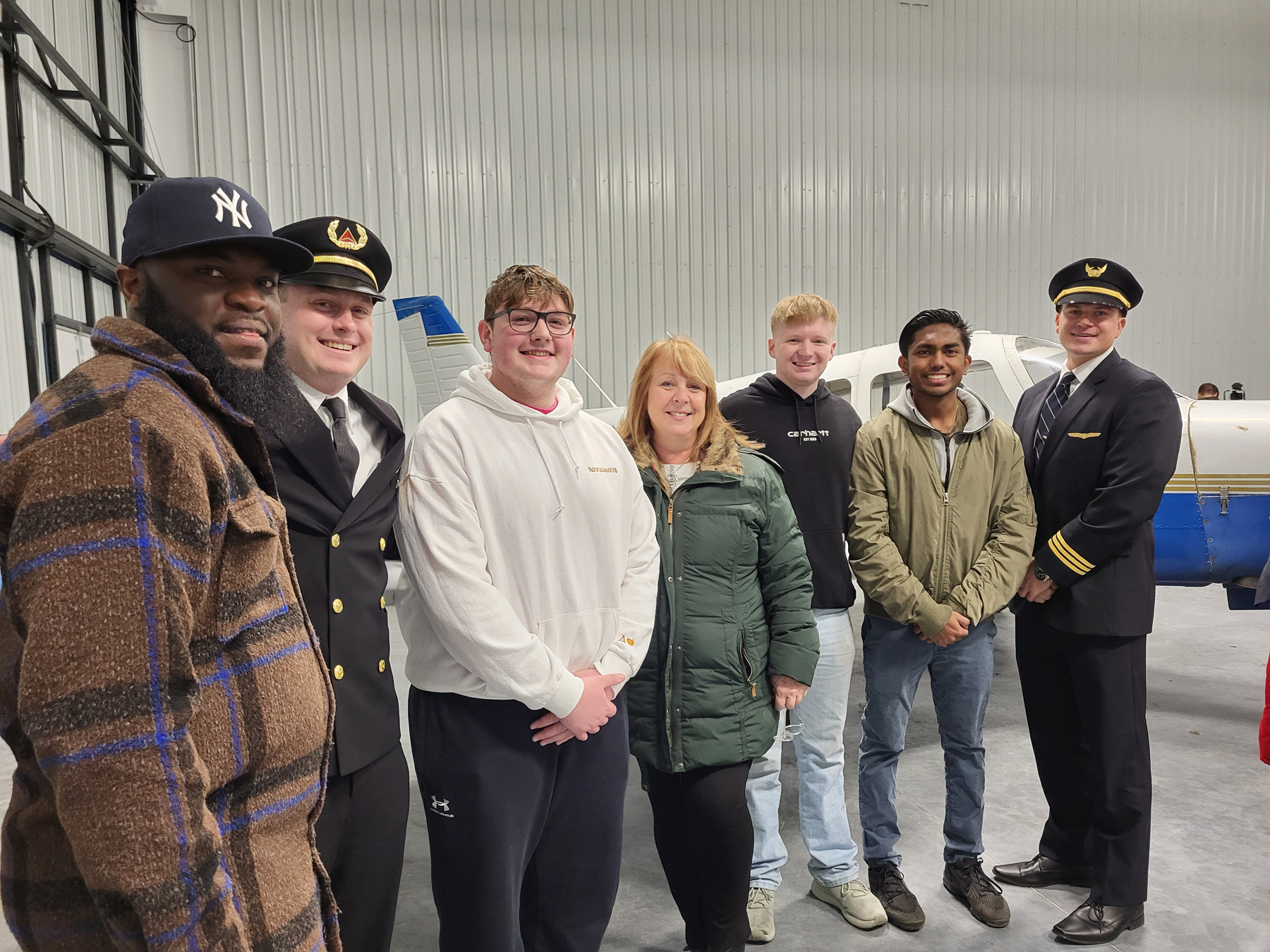 Alumni and current aviation students standing in front of plane